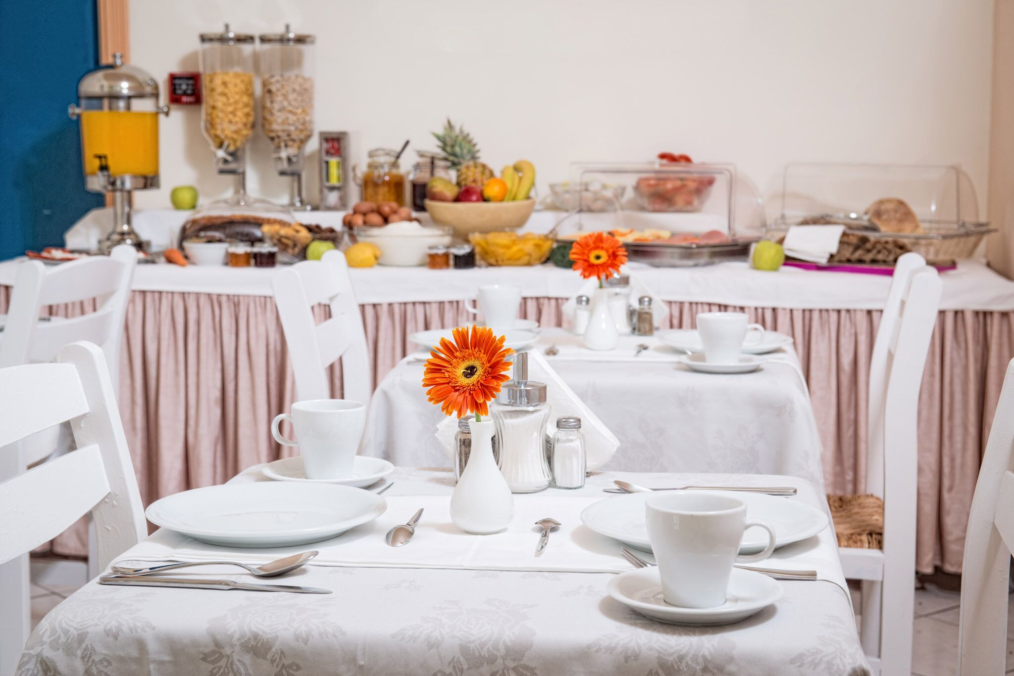 A breakfast buffet setup with various food items and a flower centerpiece.