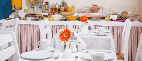 Montaje de desayuno tipo buffet con diversos alimentos y un centro de mesa floral.