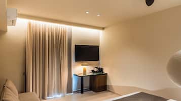 A modern hotel room with a bed, a desk with a lamp, a flat-screen TV, and a ceiling fan.