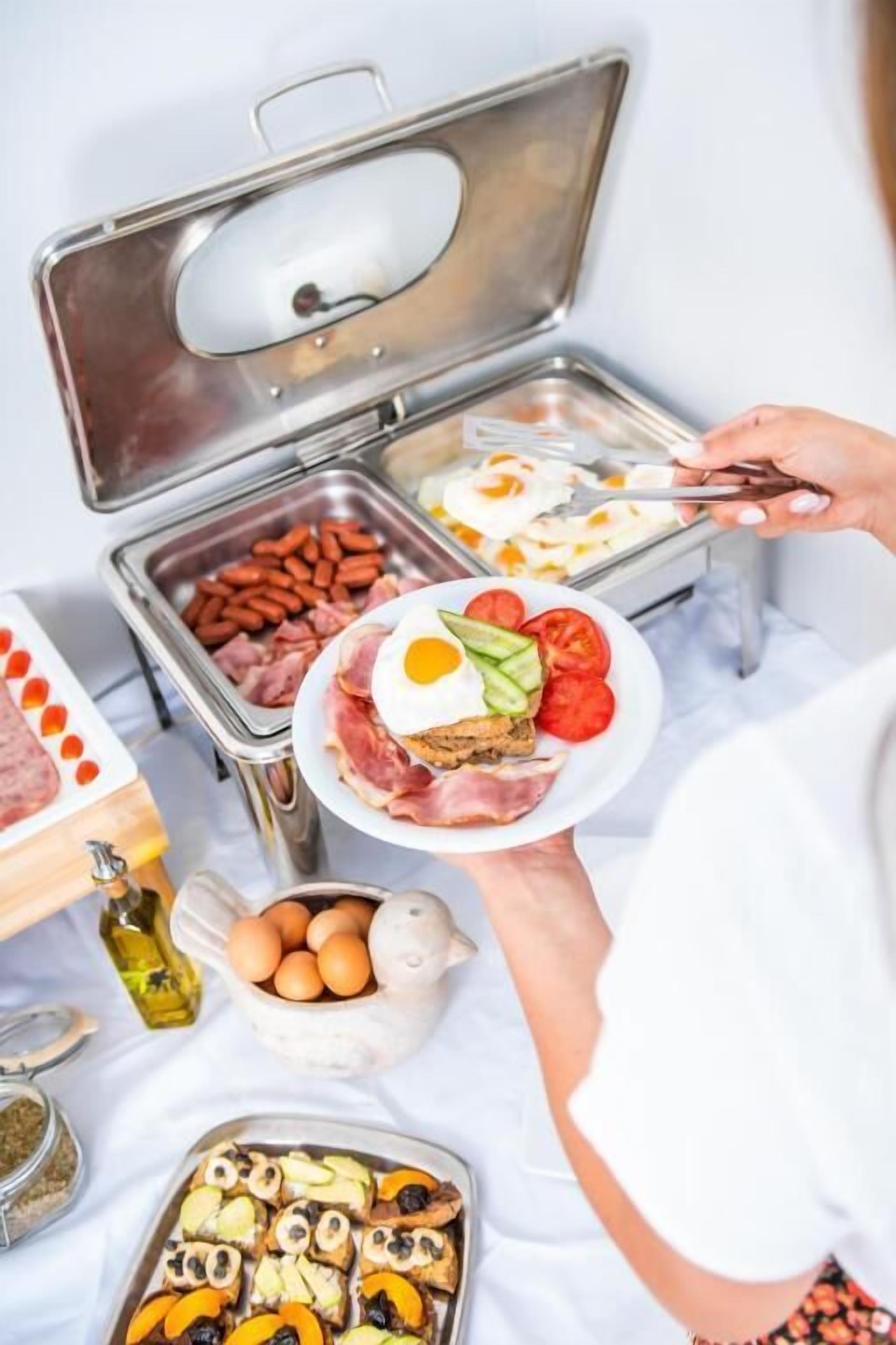 A buffet setup with various food items including eggs, meats, and vegetables.