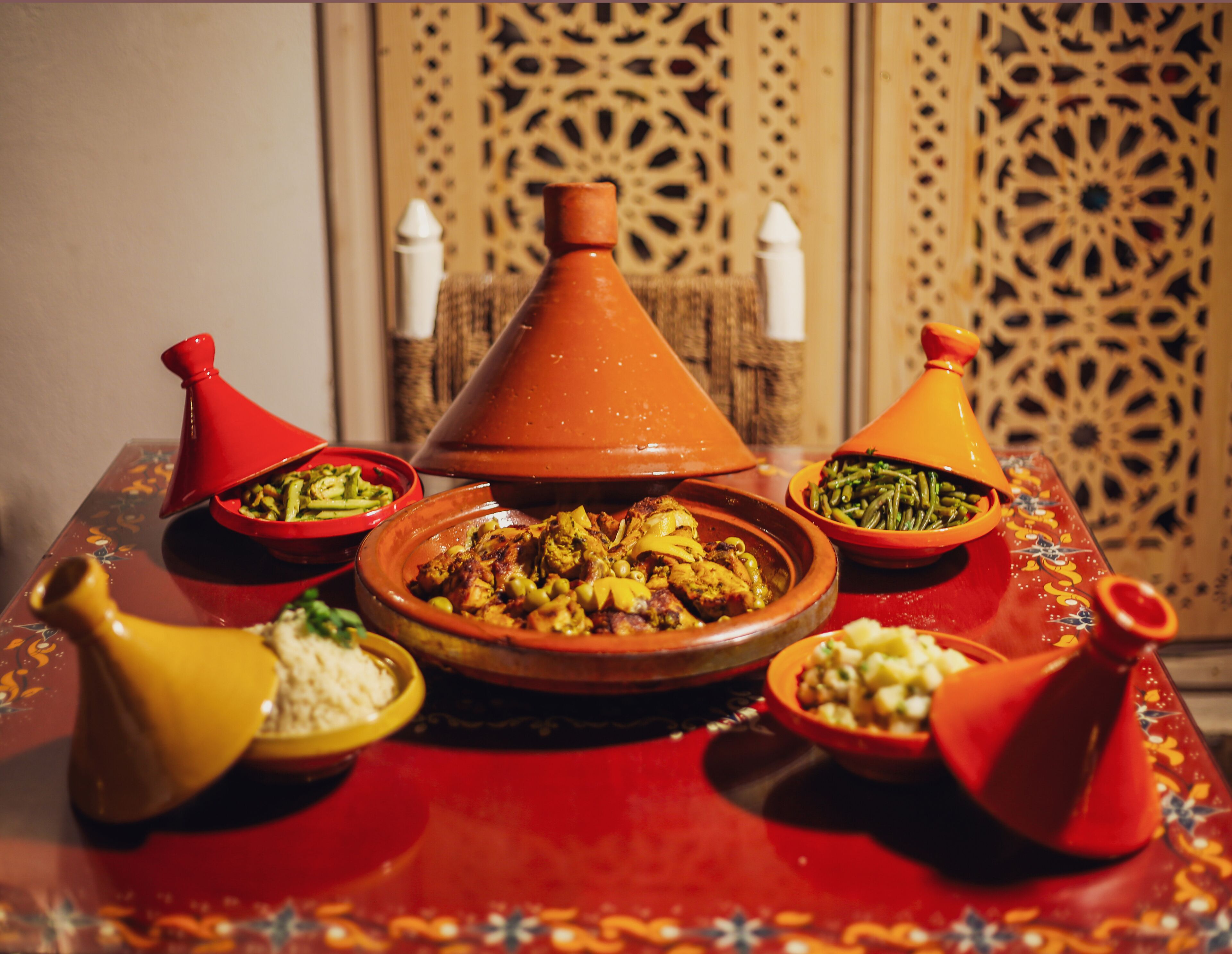A traditional Moroccan tagine set on a red table with various dishes.