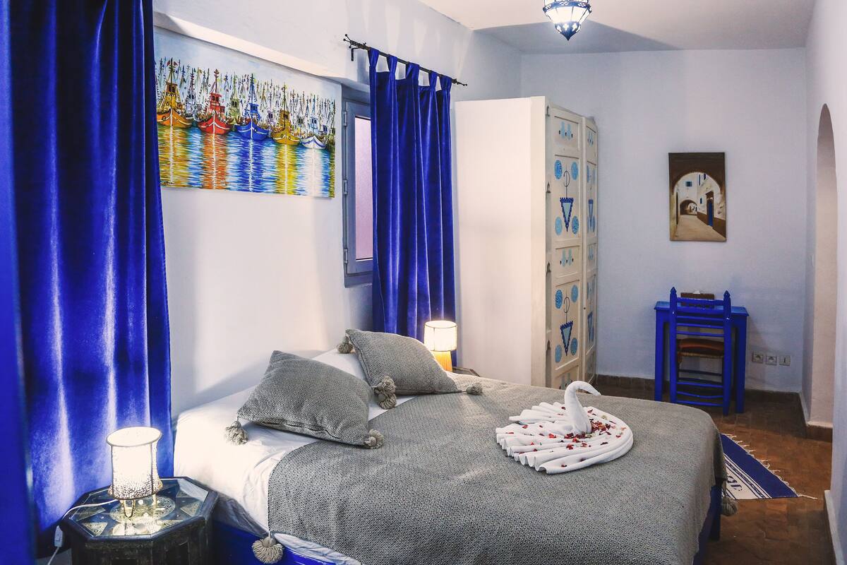 A bedroom with a bed, a nightstand, a wardrobe, and a painting on the wall.