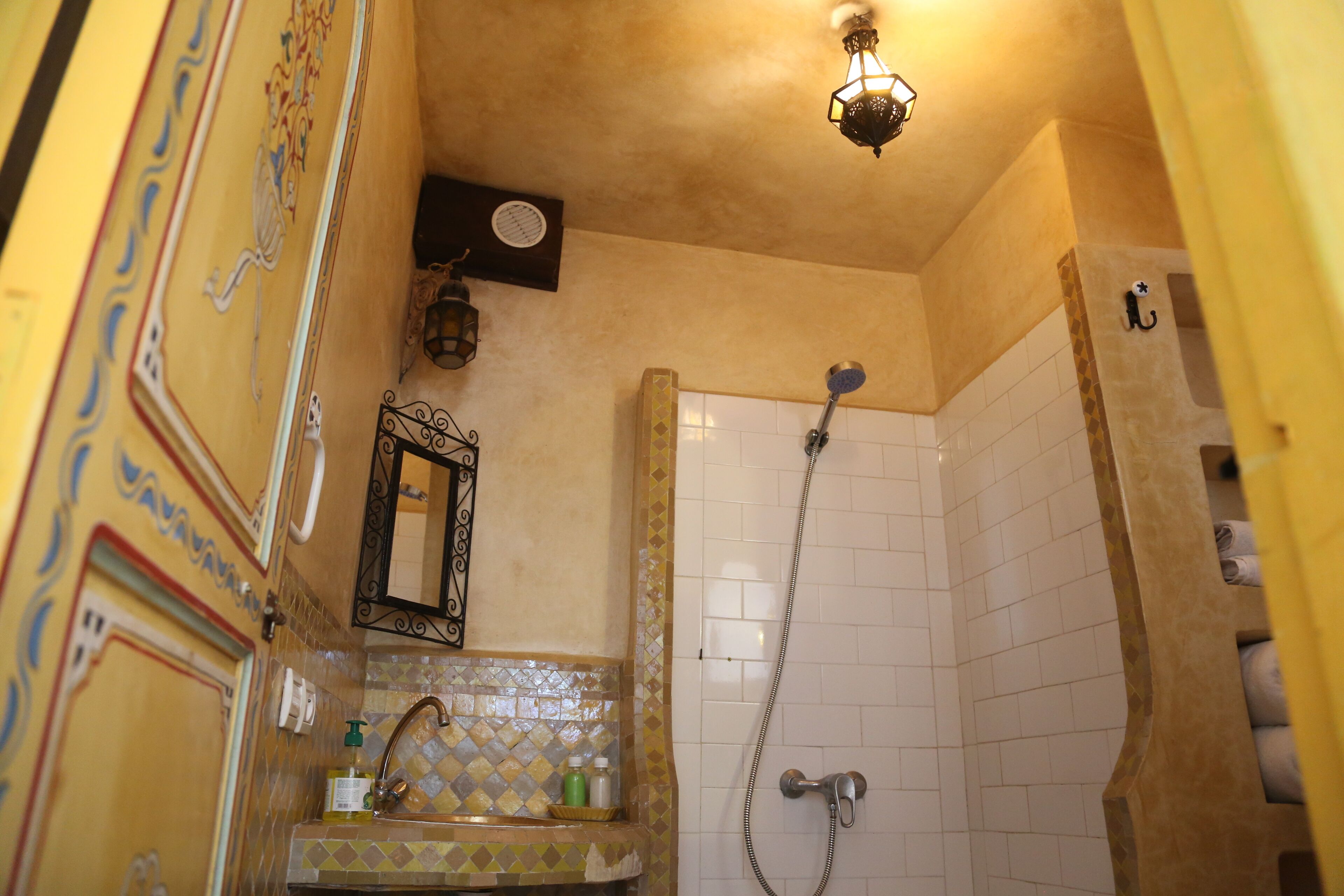 A bathroom with a shower, a sink with a decorative tile backsplash, a mirror, and a wall-mounted light fixture.