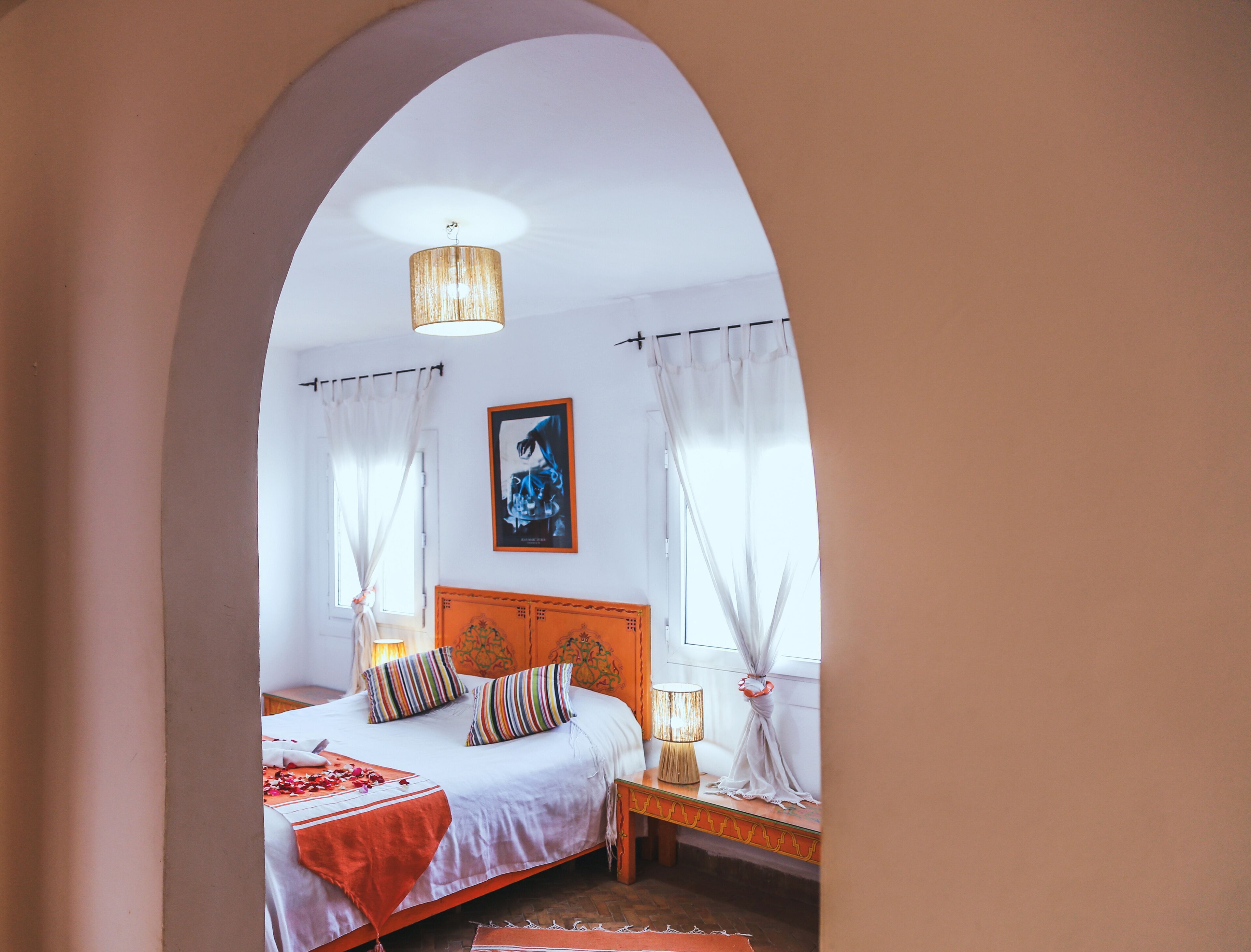 A bedroom with a bed, a nightstand, a lamp, and a painting on the wall.