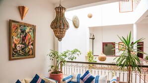 A cozy living room with a blue sofa, decorative pillows, a large painting, and potted plants. - Dar Nafoura Mogador (Essaouira)