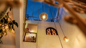 A building with a balcony, a hanging light fixture, and a window with decorative ironwork. - Dar Nafoura Mogador (Essaouira)