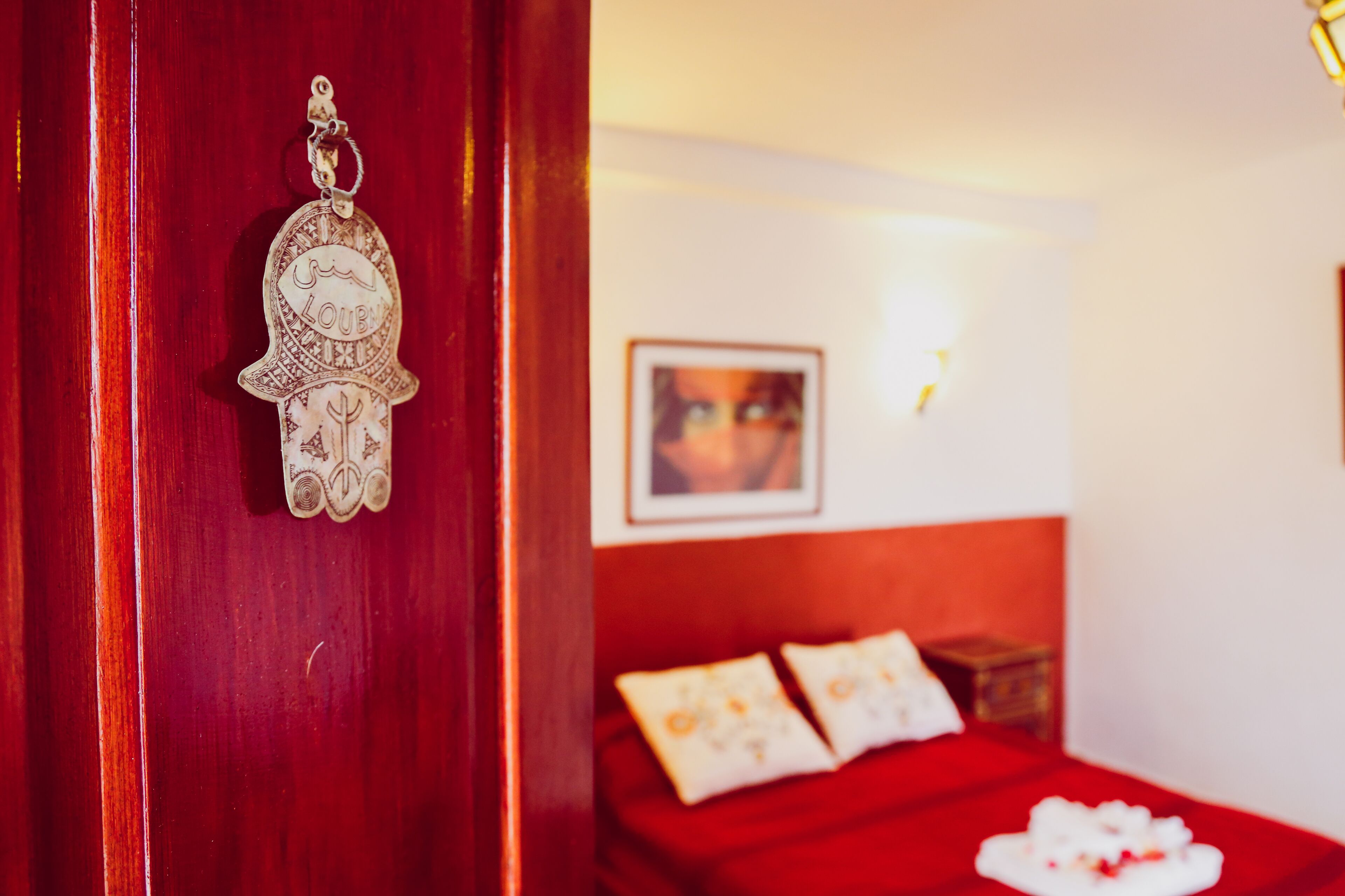 A red door with a keychain and a bed with a red bedspread and pillows.