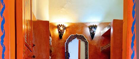 A bathroom with a red tiled wall, a white sink, and a mirror above it.