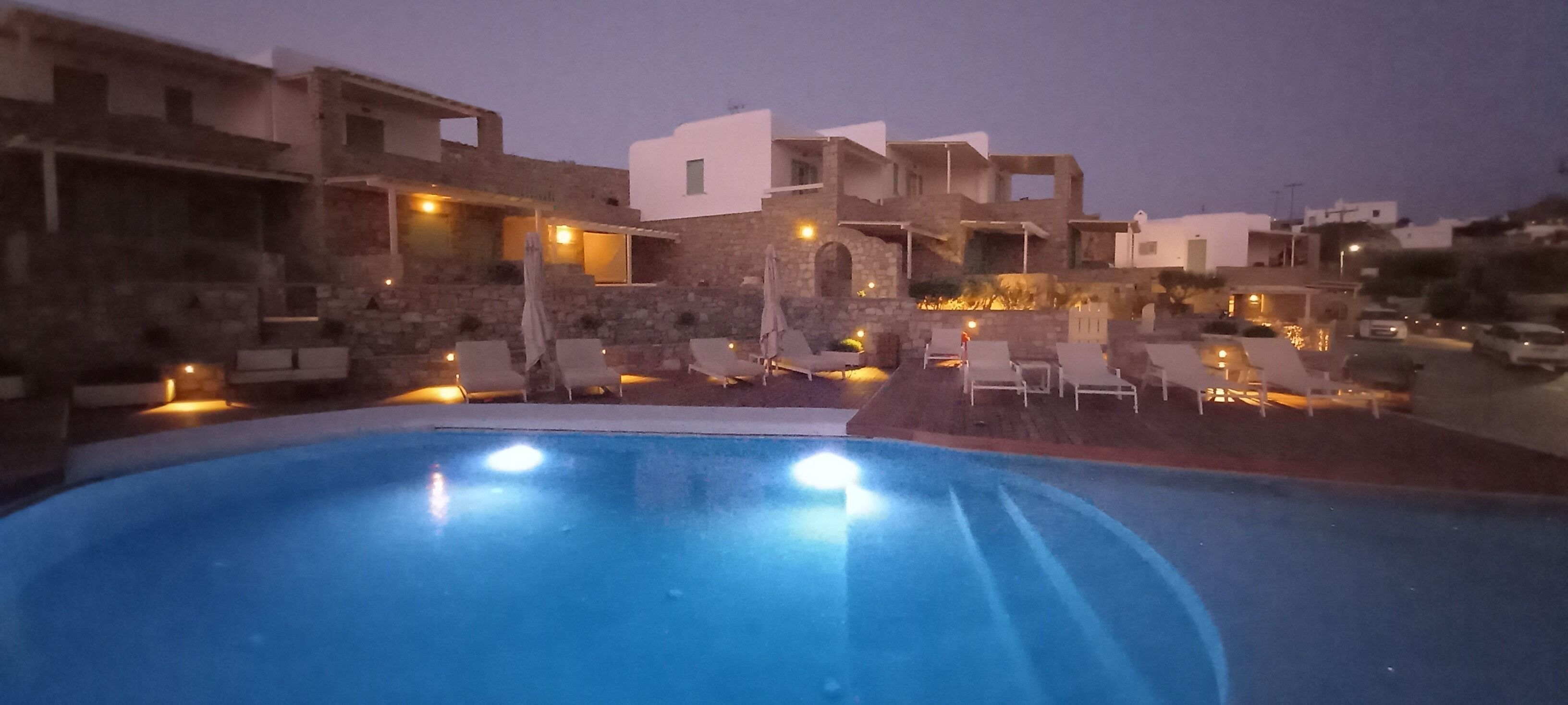 A pool area with lounge chairs and a stone building in the background.