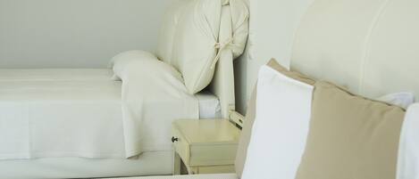 Een hotelkamer met twee bedden, een nachtkastje en wandlampen.