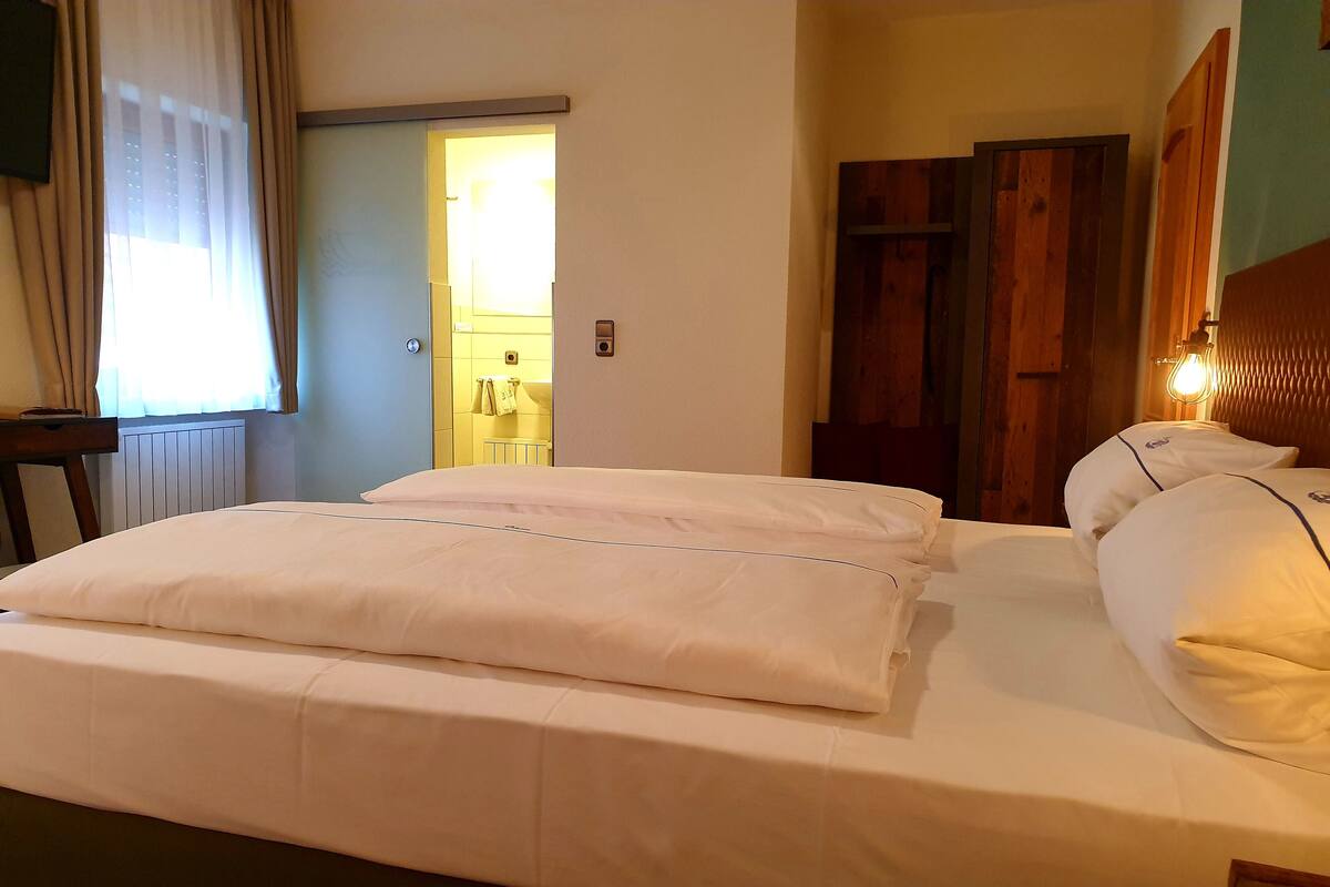 A hotel room with a bed, wooden headboard, and a nightstand.