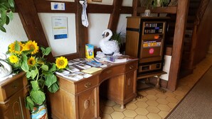 A wooden desk with a swan-shaped paperweight, a vase of sunflowers, and various papers and brochures. - Hotel Gasthof zum Schwan (Steinsfeld)