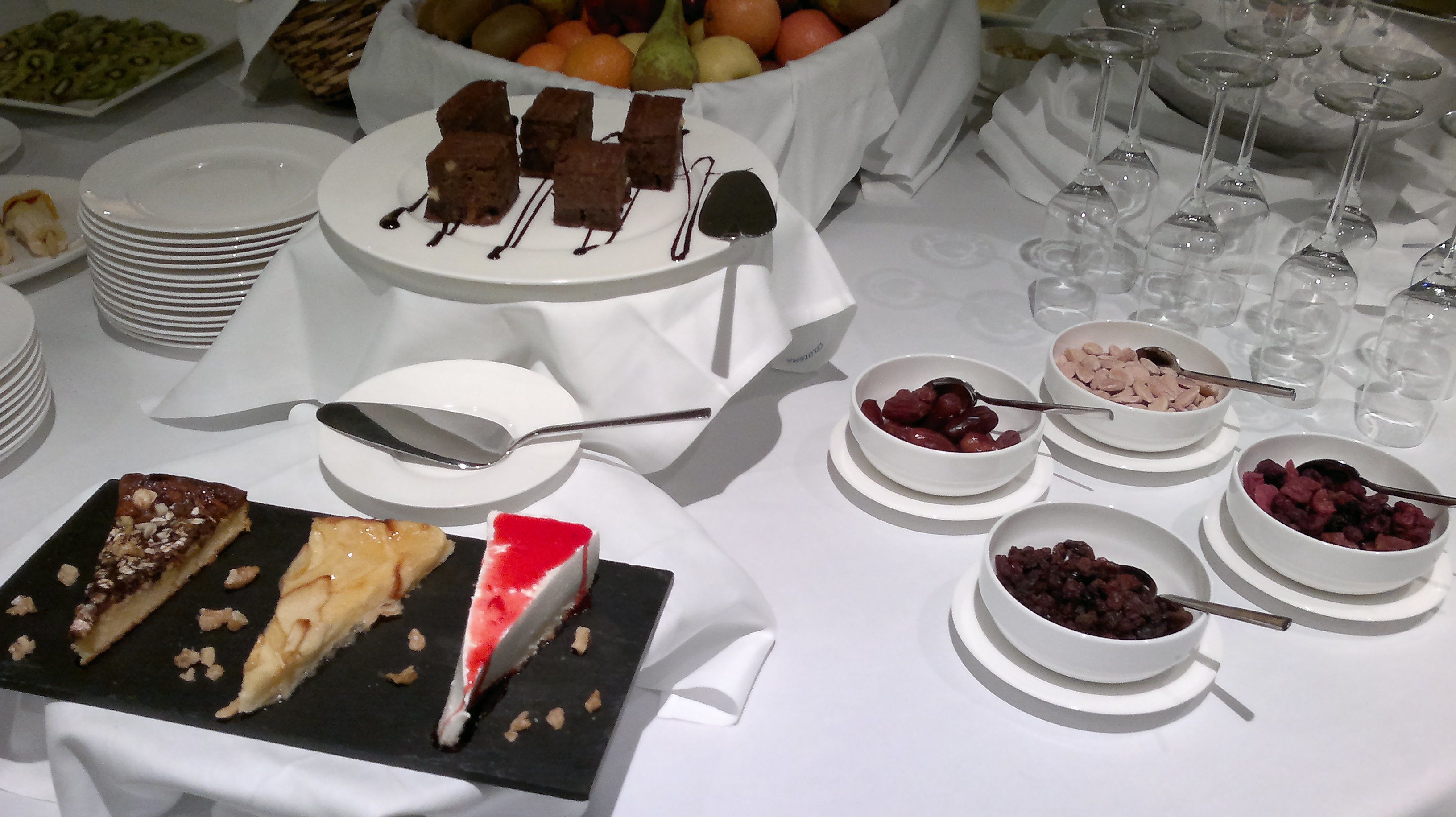 Una mesa de bufé con diversos postres, incluyendo pasteles y fruta.