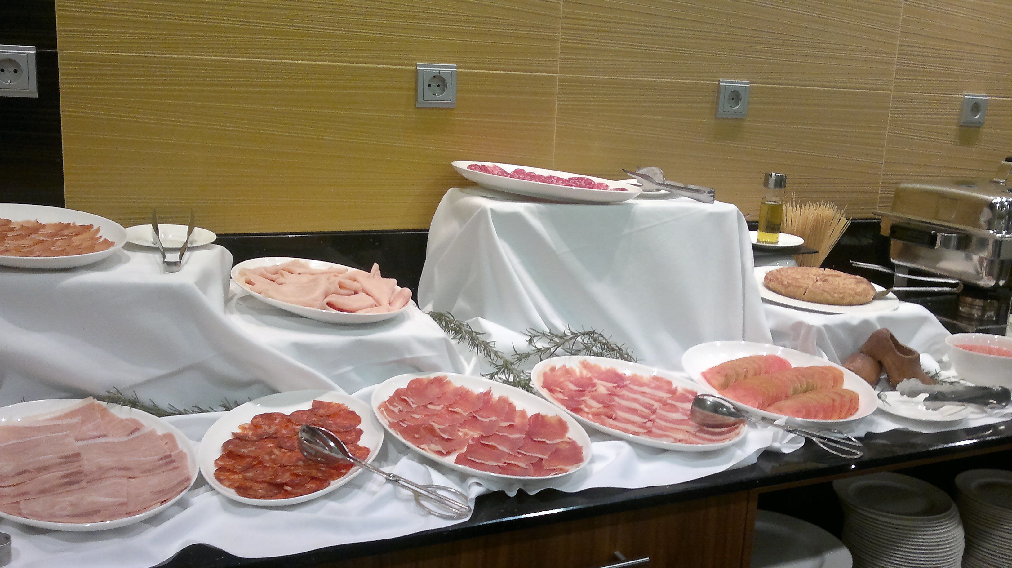 Una mesa de buffet con diversos alimentos, incluyendo embutidos y una fuente de pan.