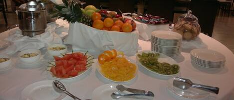 Una mesa de buffet con diversas frutas, una botella de champán y varios platos y cuencos.