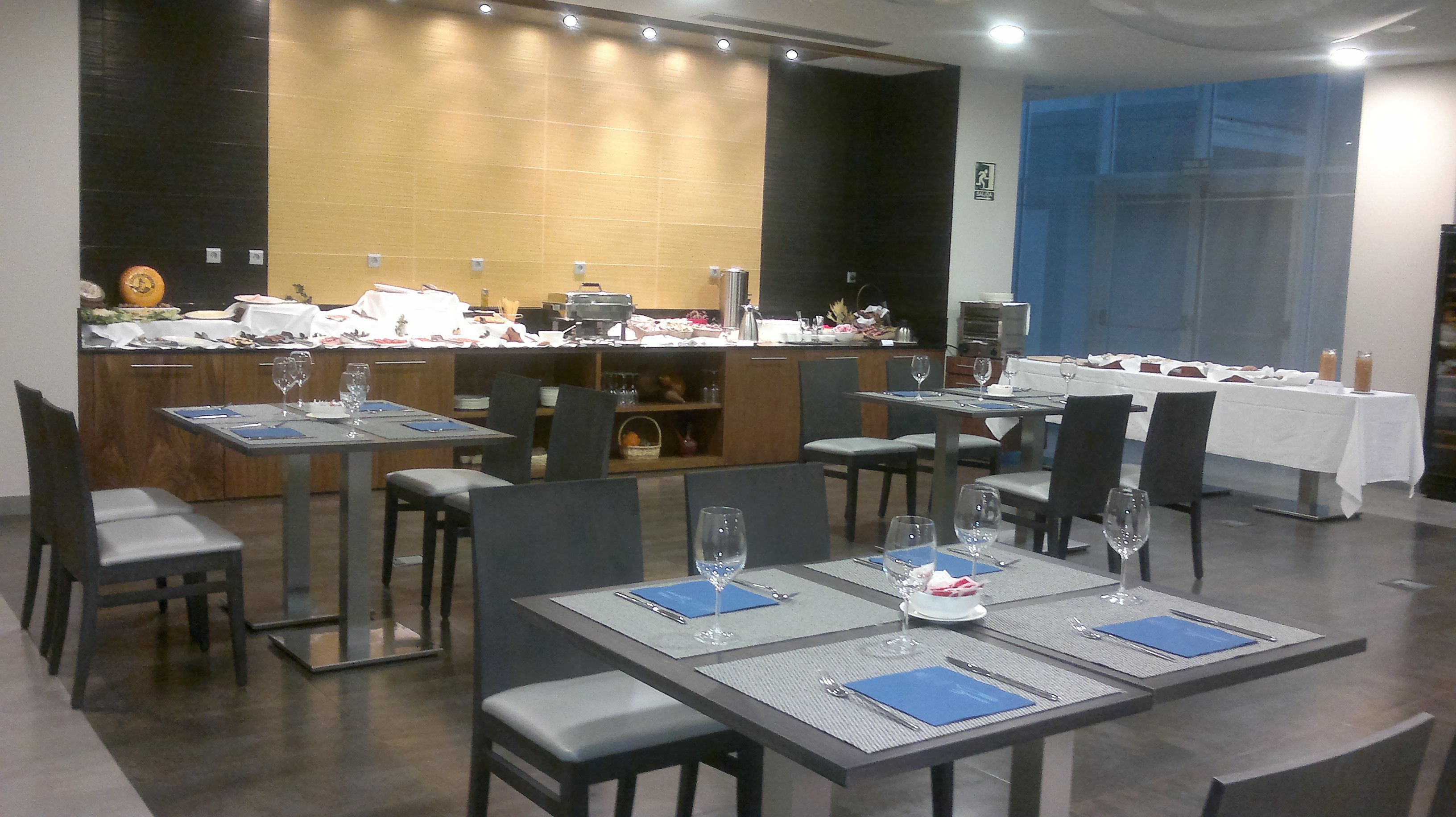 A restaurant with multiple tables set for dining, a bar area, and a counter with various items.