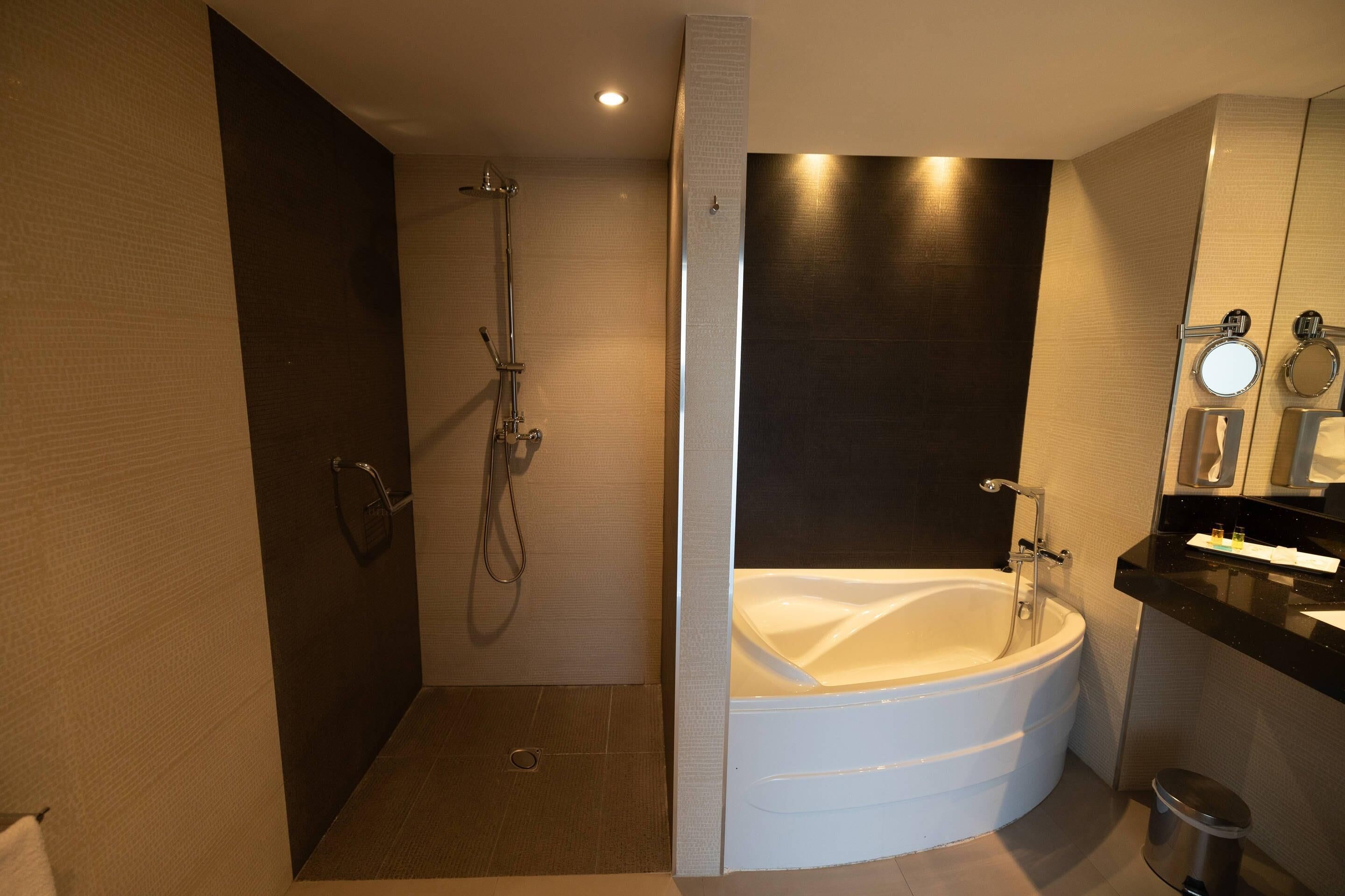 Un baño moderno con ducha a ras de suelo, bañera independiente y tocador con espejo.