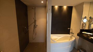 Un baño moderno con ducha a ras de suelo, bañera independiente y tocador con espejo.