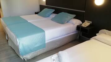 A double bed with a white and blue bedspread, two matching pillows, a bedside phone, and a nightstand.