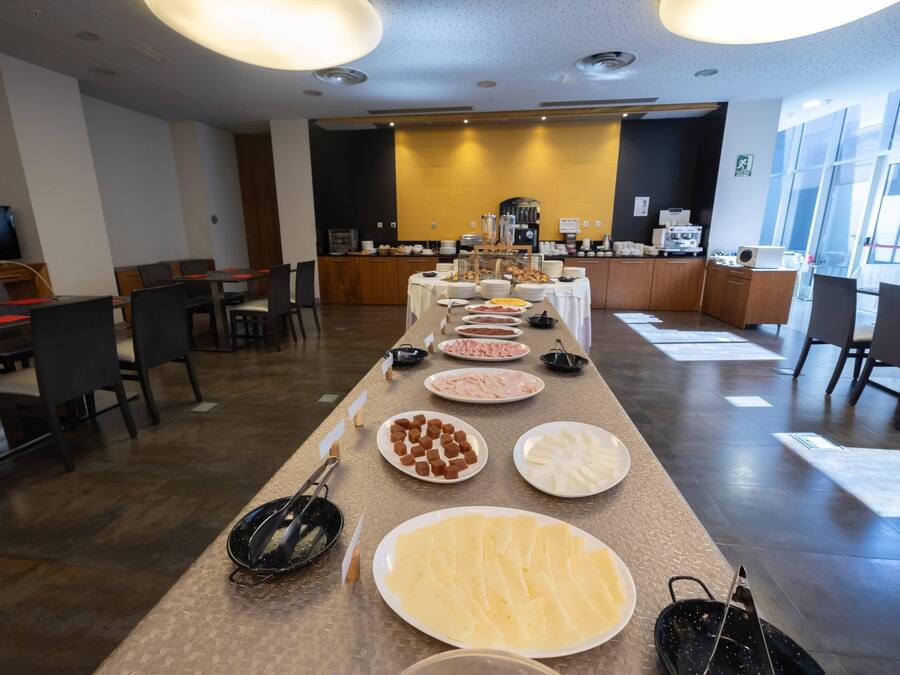 Een buffetopstelling met diverse gerechten en een koffiehoek in een moderne hotelrestaurantruimte.