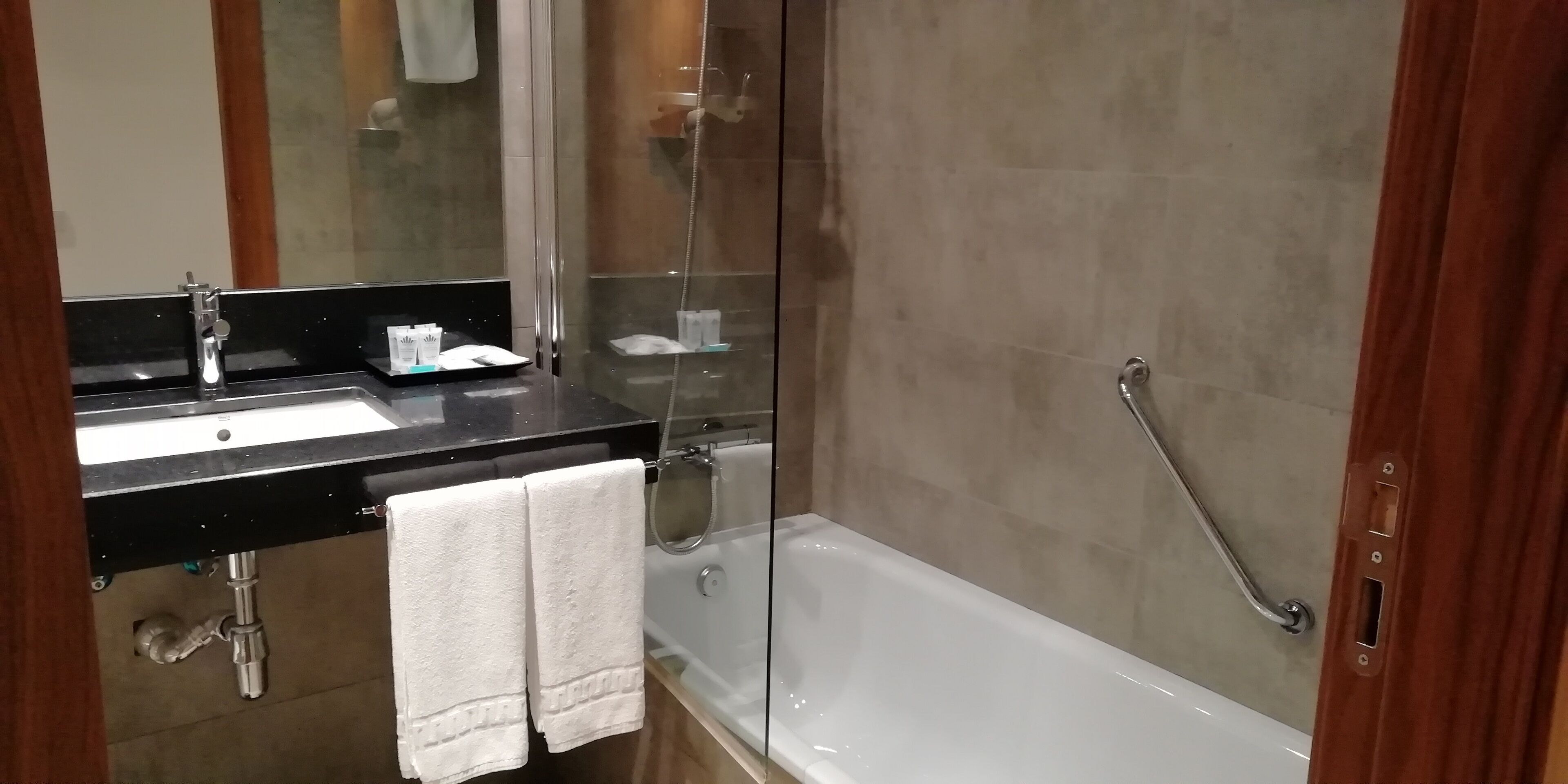 A modern bathroom with a large mirror, a sink, a bathtub, and a shower.