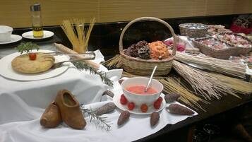 Une table de buffet proposant divers plats, notamment des pâtes, du pain et un bol de soupe.