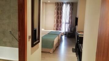 Un pasillo estrecho que conduce a un dormitorio con cama, escritorio y silla.