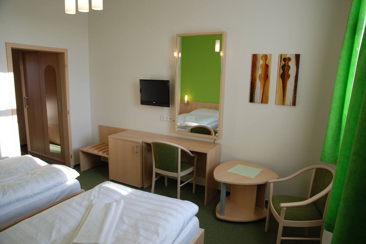 A hotel room with two beds, a desk with a chair, a television, and artwork on the wall.