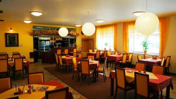 Un restaurante con varias mesas y sillas, una zona de bar y farolillos decorativos.