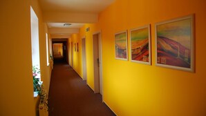 Un pasillo de hotel con paredes amarillas, obras de arte enmarcadas y piso alfombrado.