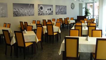 A dining area with tables and chairs, artwork on the walls, and a clock.