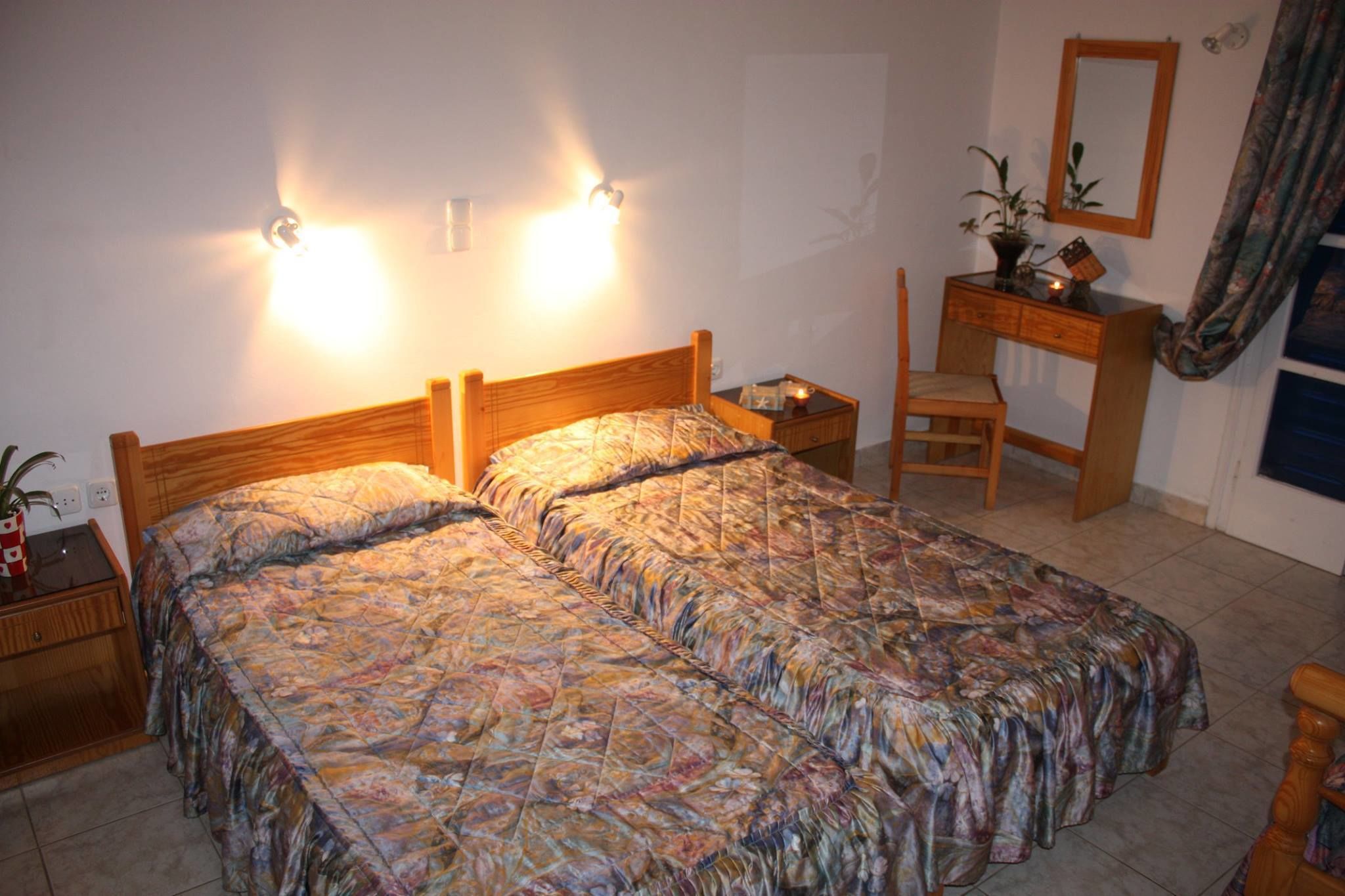 A bedroom with a double bed, bedside tables, a wooden dresser, a chair, and a mirror.