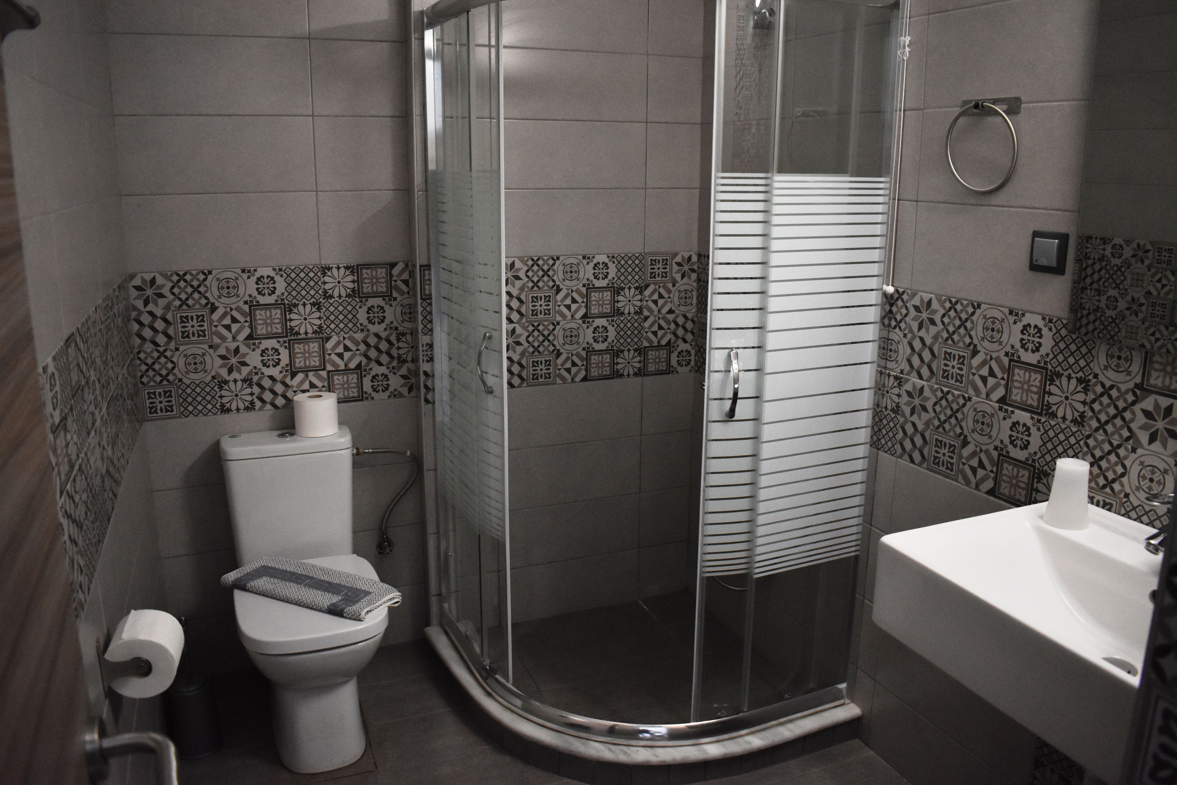 A bathroom with a toilet, a shower enclosure, and a sink.