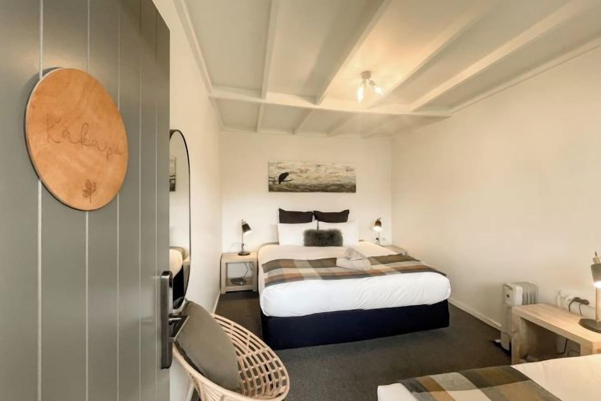 A bedroom with a bed, bedside tables, a chair, a desk, and a wall-mounted circular object.