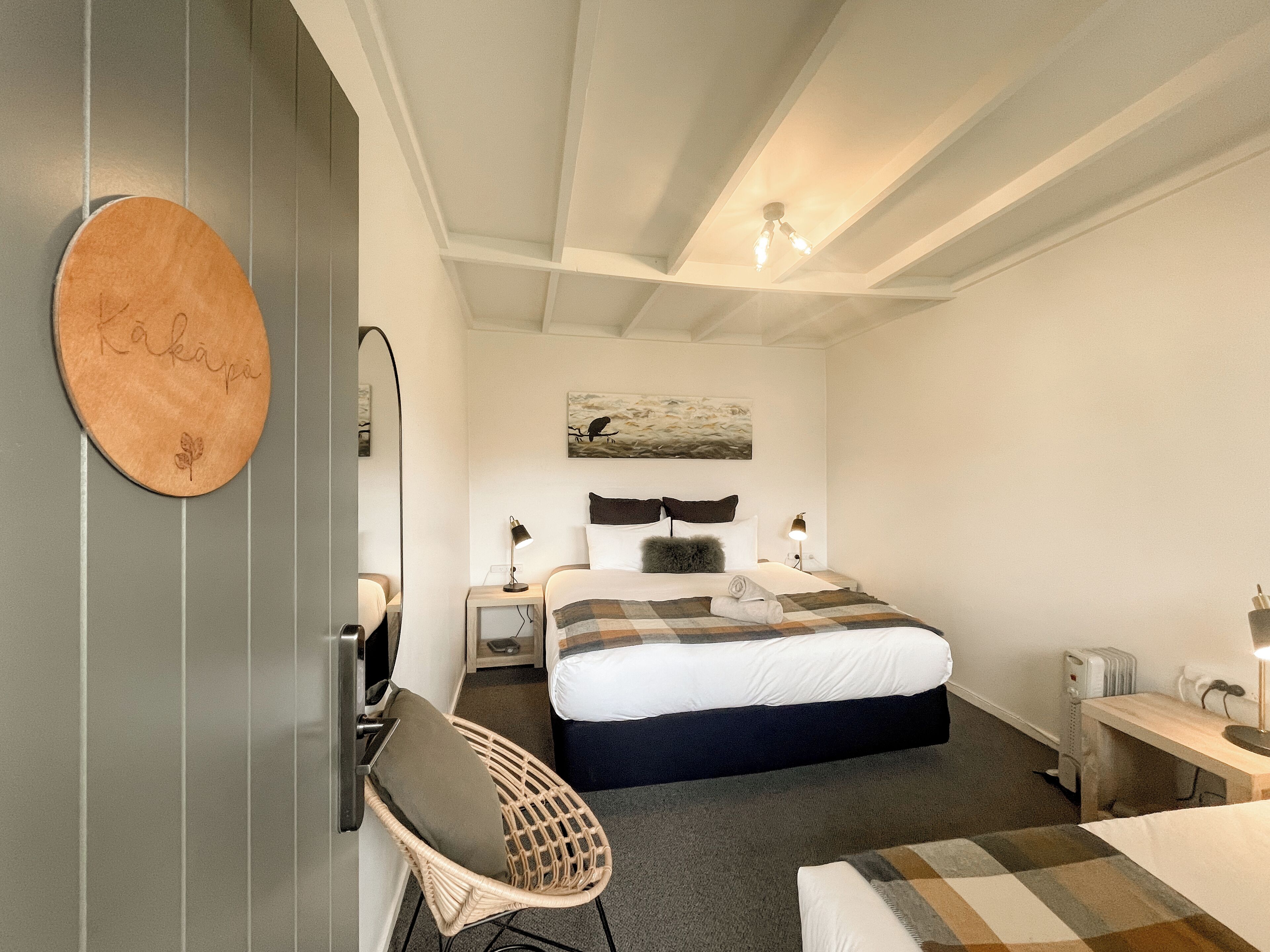 Une chambre d’hôtel comprenant un lit, une chaise, un bureau, un miroir et une œuvre d’art accrochée au mur.
