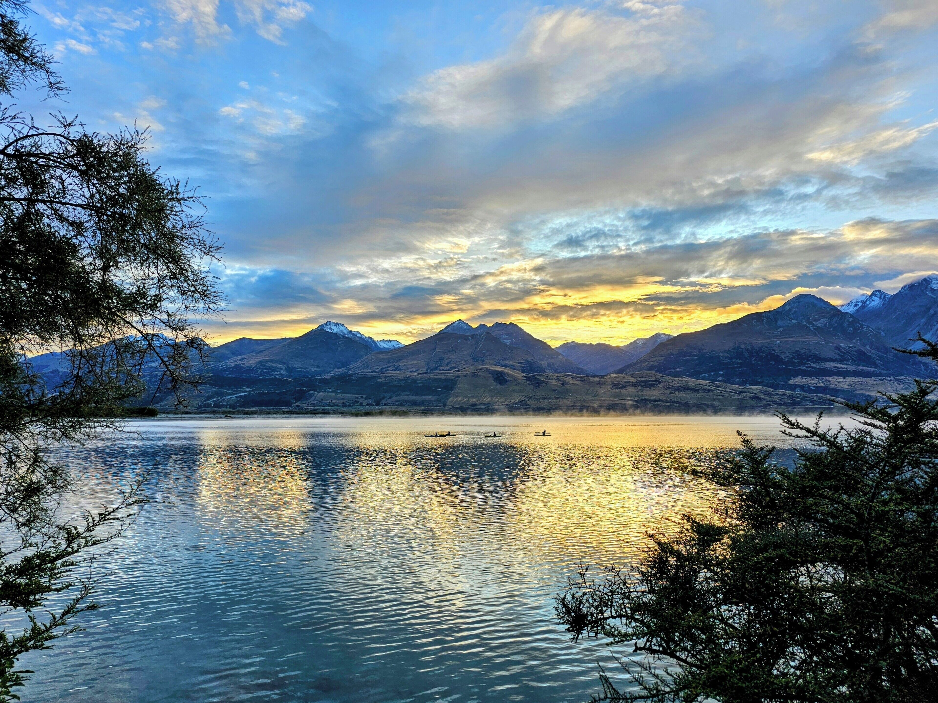 Un lago sereno con montañas al fondo y un cielo despejado.