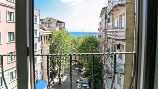 A narrow street with parked cars and buildings on either side.