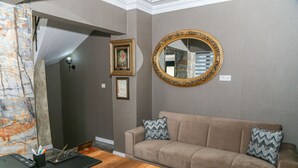 A room with a beige sofa, a wooden coffee table, a mirror with an ornate frame, and a framed picture on the wall.