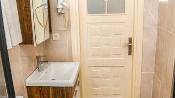 Une salle de bain avec un lavabo blanc, un miroir, des toilettes et une porte ornée d’un motif géométrique.