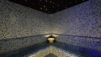 Unique mosaic tile design adorns the walls and floor, creating a geometric pattern. A central light fixture and ceiling lights provide illumination.