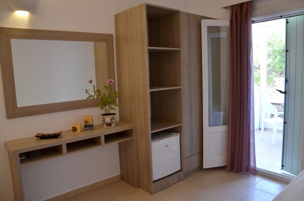 A room with a wooden cabinet, a small refrigerator, a mirror, and a potted plant. - Galaxy (Ios)