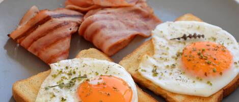 A plate with two fried eggs on toast, accompanied by strips of bacon.