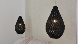 Een slaapkamer met een bed, twee hanglampen, een nachtkastje en een muur met een reliëfstructuur.