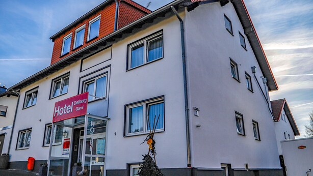 Un hotel con un letrero rojo, varias ventanas y fachada blanca.