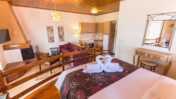 Un dormitorio con cama, una escalera de madera, una zona de estar con sofá, una mesa de comedor y una cocina.