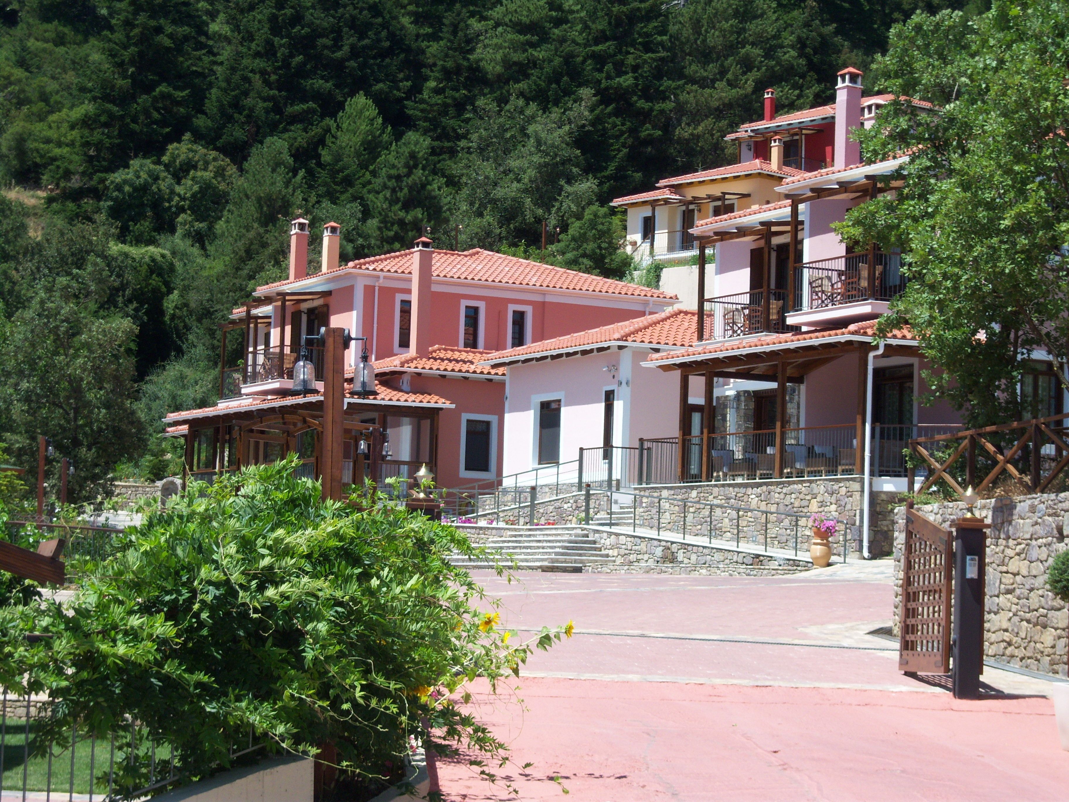 A multi-story building with a red-tiled roof, a stone staircase, and a balcony.