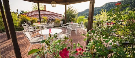 A covered patio with outdoor furniture and a view of a mountain.