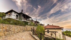 A stone staircase leading to a house with a balcony, surrounded by greenery and a stone wall. - Ilaeira Mountain Resort (Sparta)