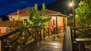 A wooden bridge leading to a house with a tiled roof and a lit lamp post. - Ilaeira Mountain Resort (Sparta)