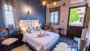 A bedroom with a large bed, a chair, a small table, and a view of the outside. - Ilaeira Mountain Resort (Sparta)